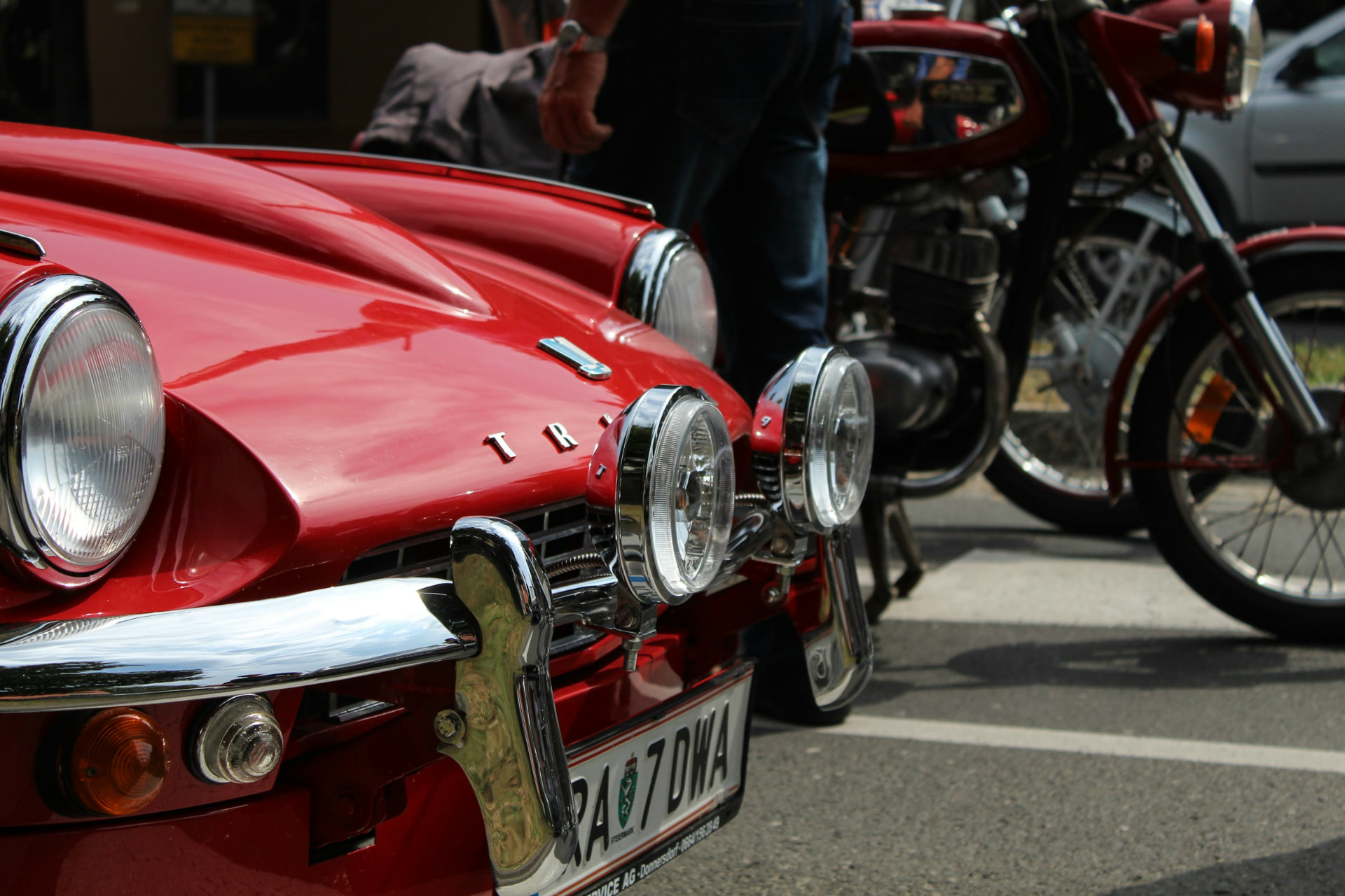 Rode Triumph oldtimer met chromen koplampen naast klassieke motoren